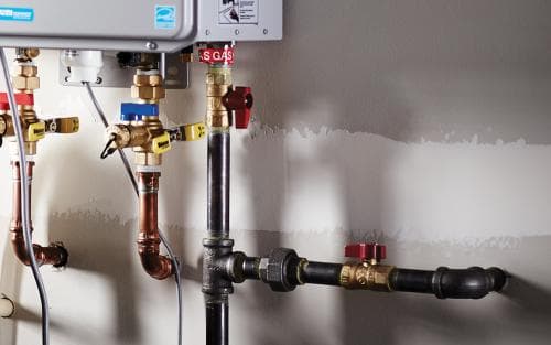 Pipes and valves in a plumbing system connected to a gas water heater installation.
