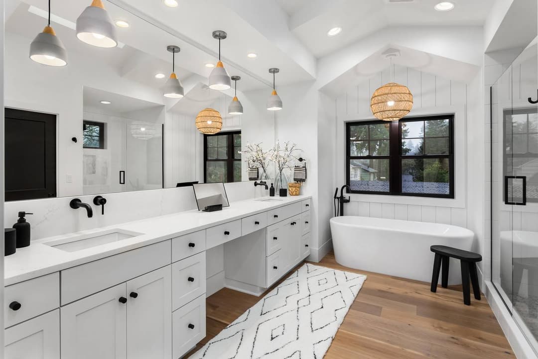 Modern white bathroom with double sink, freestanding tub, and sleek black fixtures.