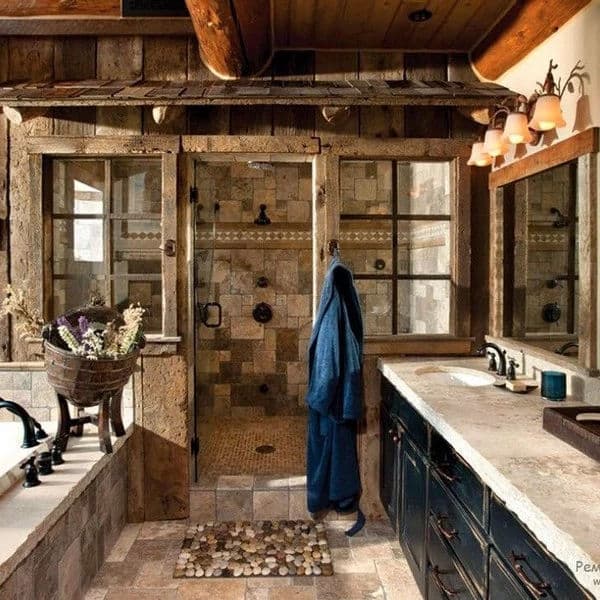 Rustic bathroom with stone tiles, glass shower, wooden accents, and vintage decor elements.